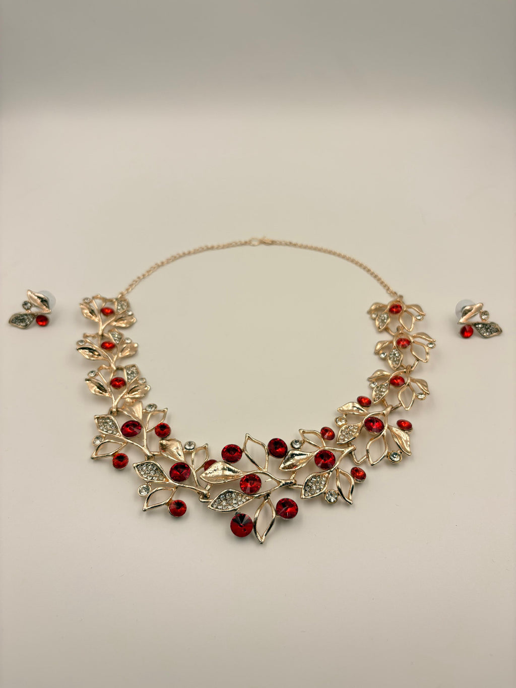 Necklace with red stones and matching earrings on a light gray background